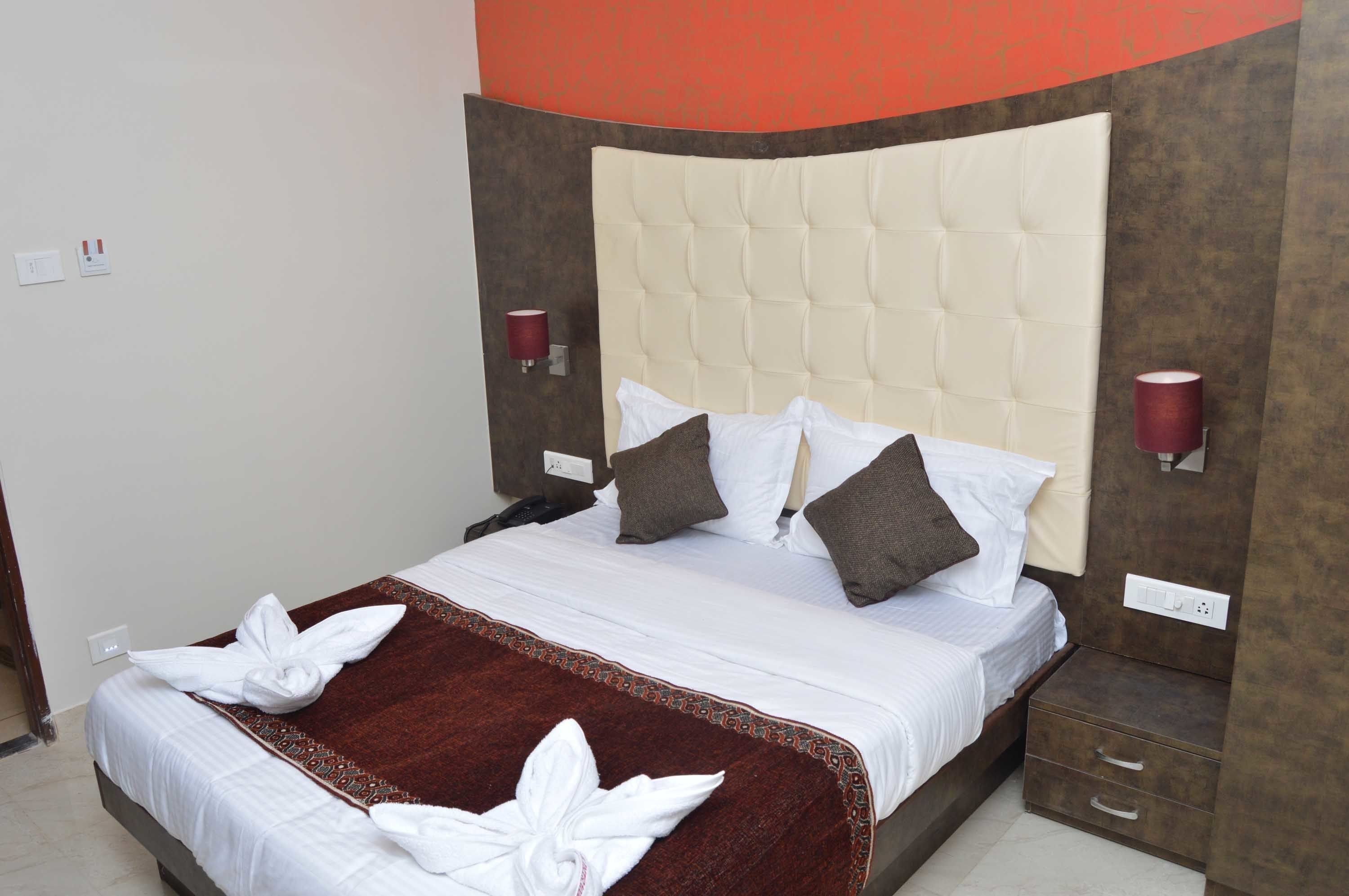 A neatly made bed with a red and white patterned bedspread, two pillows, and a folded towel on the side.