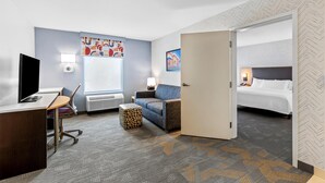 A hotel room with a desk, chair, sofa, and a bed.