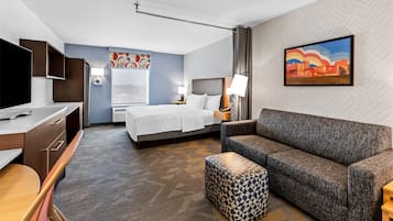 Una habitación de hotel con cama, sofá, escritorio y televisor.