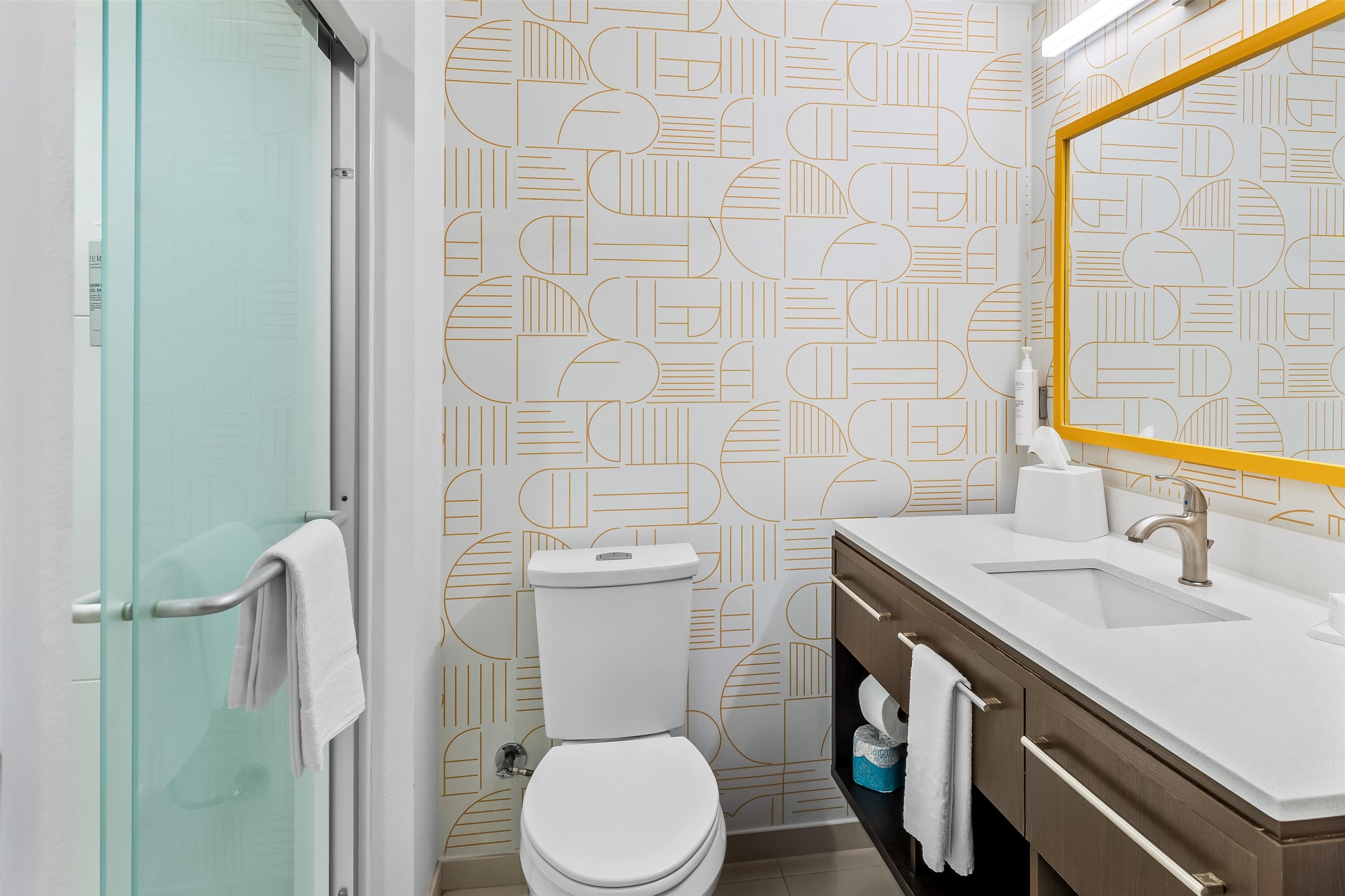Un baño moderno con inodoro, lavamanos y espejo.