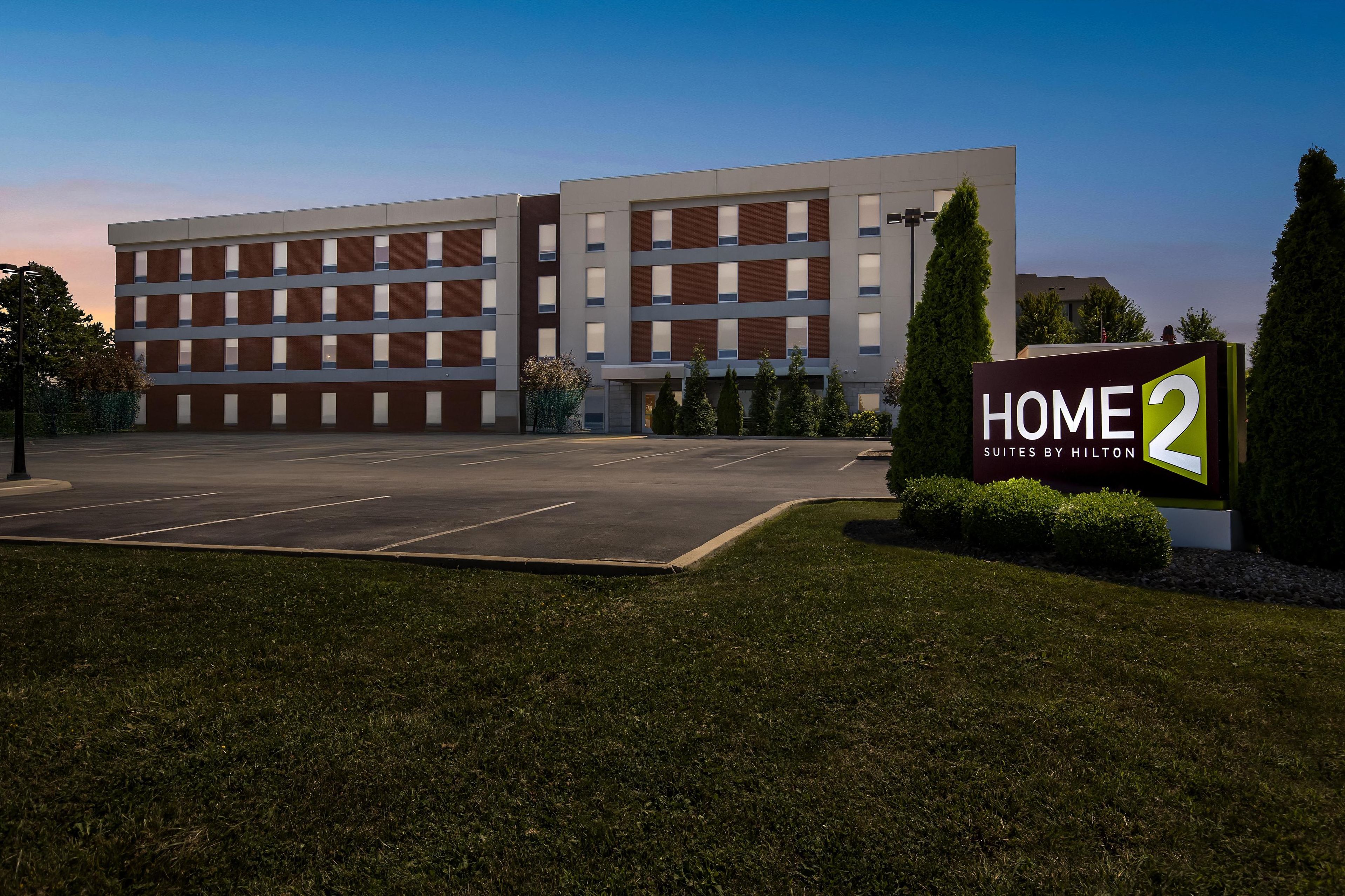 Un edificio moderno de hotel con un cartel que dice 'HOME 2 Suites by Hilton'.