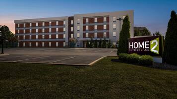 Un edificio moderno de hotel con un cartel que dice 'HOME 2 Suites by Hilton'.