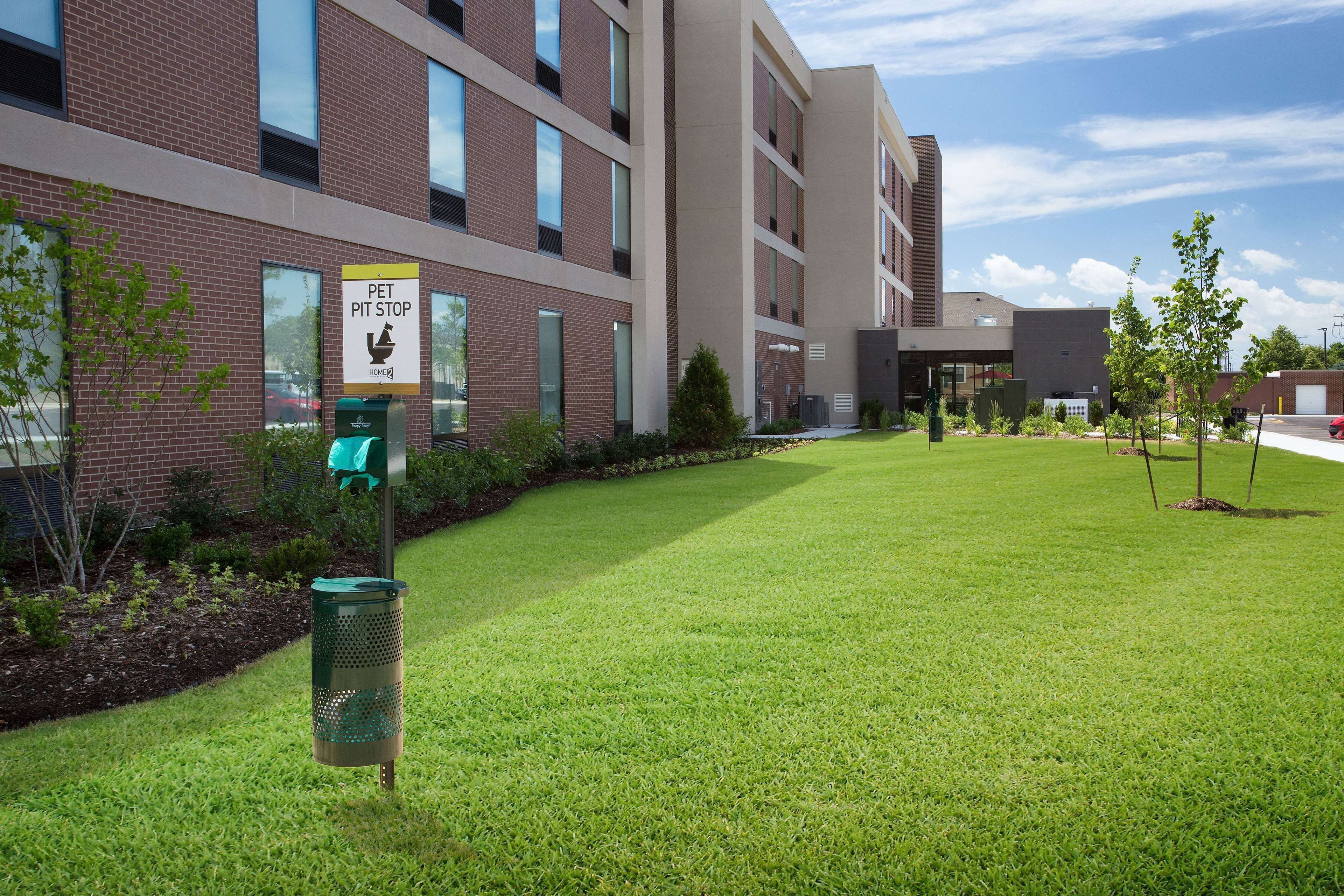 A pet-friendly building with a grassy courtyard, a pet waste station, and a sign indicating a pet pit stop.
