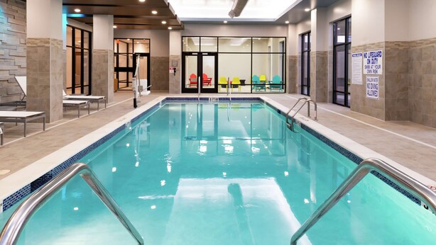 An indoor swimming pool with clear water, surrounded by tiled walls and benches. - Home2 Suites by Hilton Columbia Downtown (Columbia)