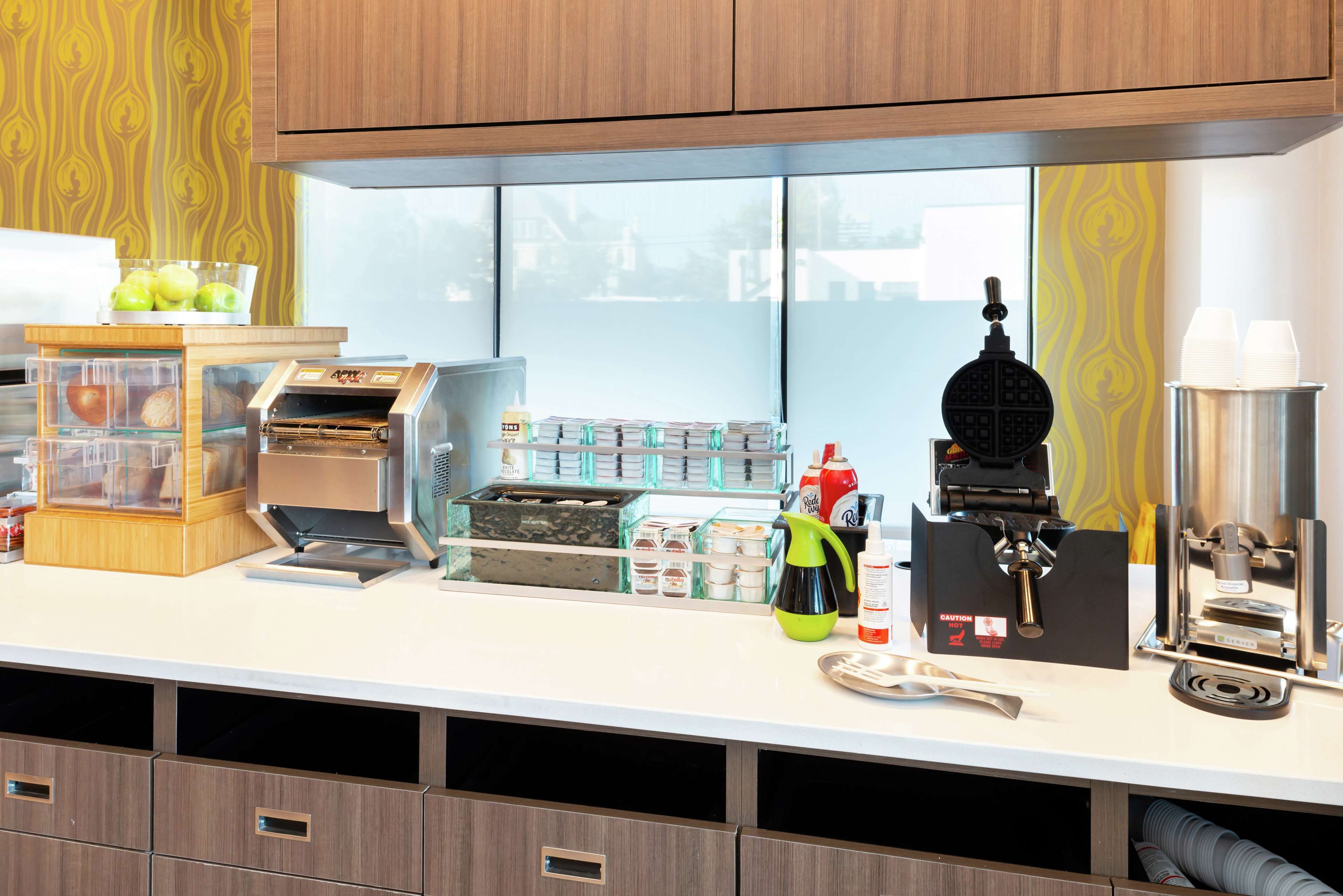Een keuken met een koffiezetapparaat, een wafelijzer en diverse keukenapparaten.