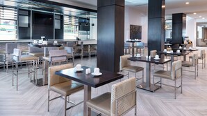 A modern hotel lobby with multiple seating areas, including round tables and chairs, and a large central pillar. - Home2 Suites by Hilton Columbia Downtown (Columbia)