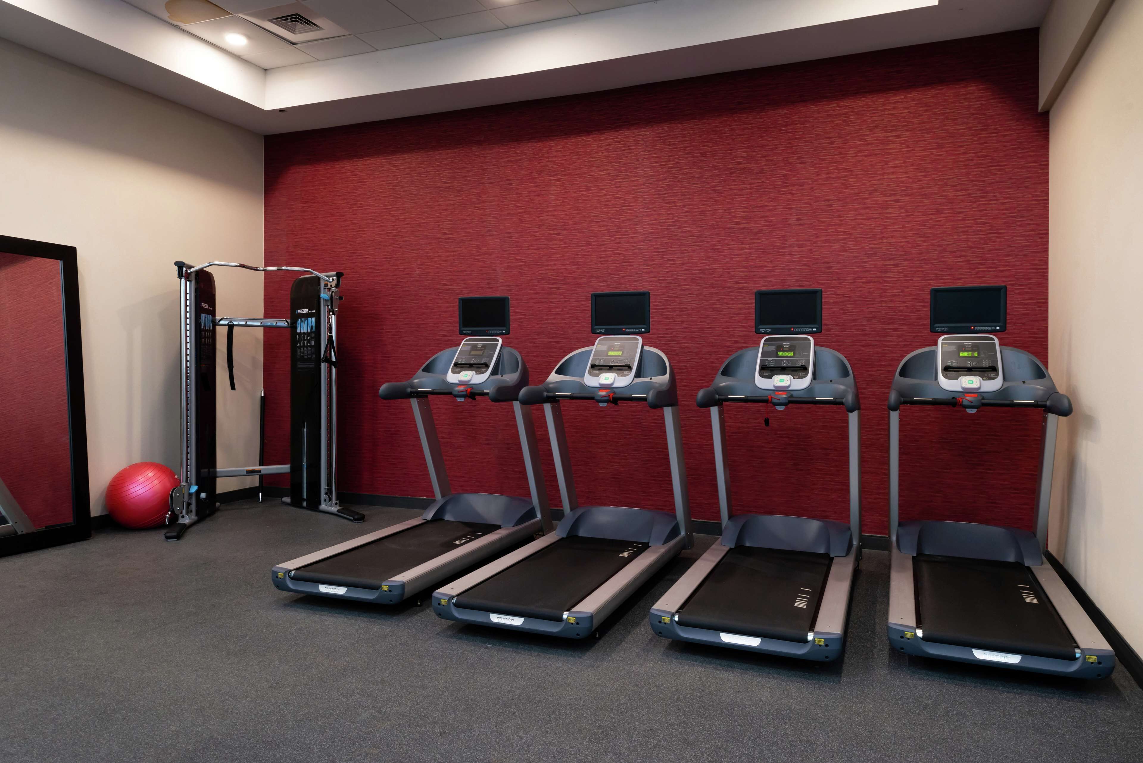 A gym with treadmills, a stationary bike, and a red exercise ball.