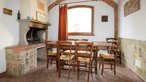 Comedor con chimenea de ladrillo, sillas de madera y una mesa.
