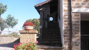 Un escalier en pierre menant à l’entrée d’un bâtiment, qui est fermée par un portail en métal.