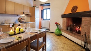 Un coin repas avec une table dressée pour quatre personnes, des bougies et un vase de fleurs.