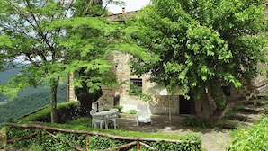 Un bâtiment rustique en pierre, doté d’un petit patio, d’une table et d’une chaise.