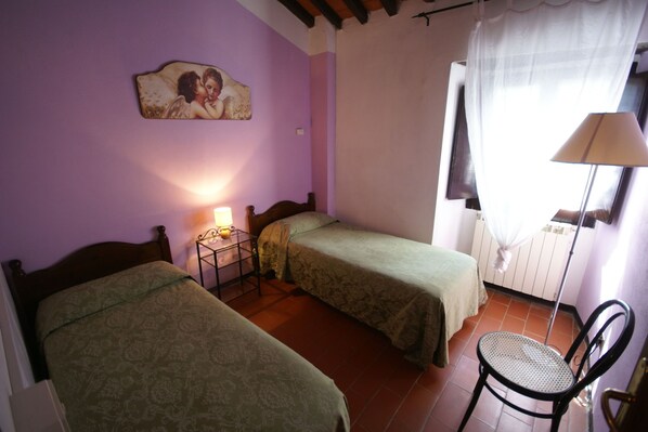 A bedroom with two single beds, a bedside table with a lamp, a chair, a wall-mounted picture, and a window with a curtain. - Farmhouse in Dicomano with Tuscan Views (Dicomano (fi))