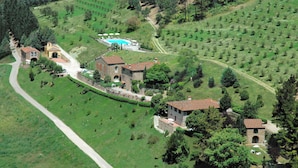 Vue aérienne d’un domaine rural comprenant plusieurs bâtiments, une piscine et des champs en terrasses.
