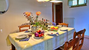 Une table à manger dressée avec des assiettes, des verres et un saladier rempli de fruits.