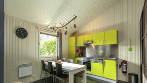 Een compacte keuken met een eethoek, met een witte tafel, stoelen en een klein krukje.