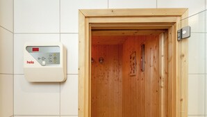 Een sauna met houten inrichting en een bedieningspaneel met de tekst 'helo' op de wand.