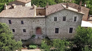Ein Steinhaus mit Ziegeldach, mehreren Fenstern und einem zentralen Bogenportal.
