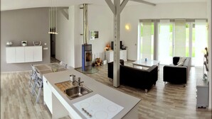 Uma cozinha moderna com uma ilha central, eletrodomésticos embutidos e um espaço de jantar com sofá.