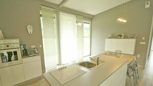 Cozinha moderna com uma ilha grande, forno embutido e janela que proporciona luz natural.