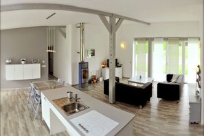 A modern kitchen with a central island, built-in appliances, and a dining area with a sofa.