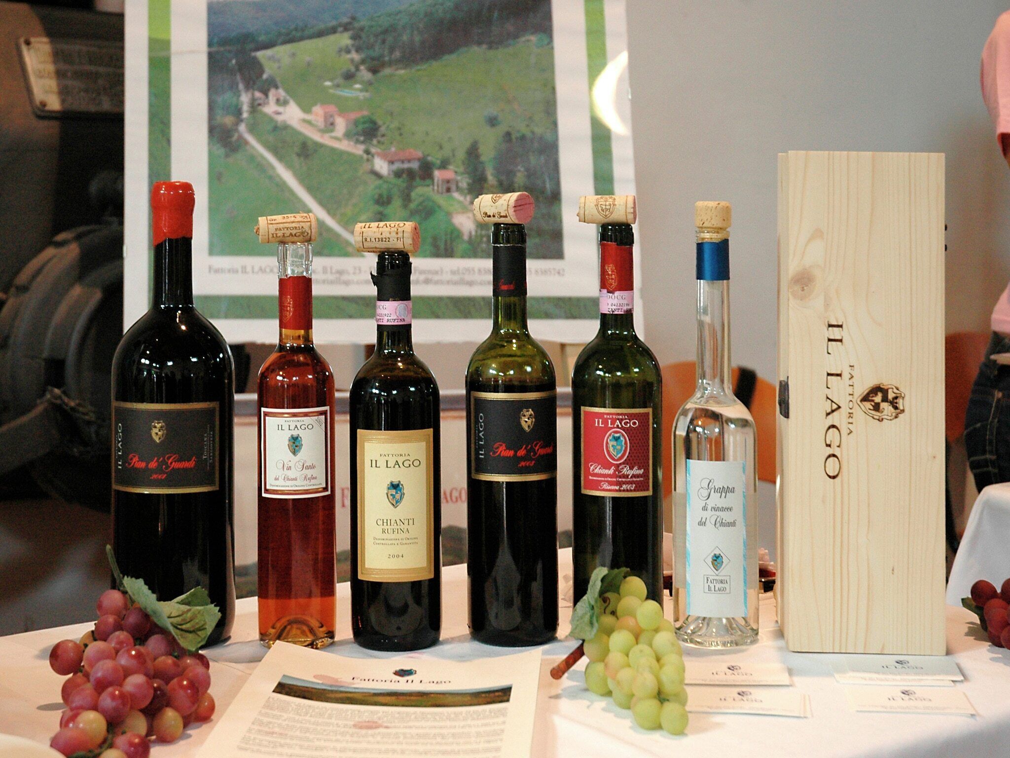 Uma mesa com várias garrafas de vinho e uma caixa de madeira com a inscrição 'IL LAGO'.