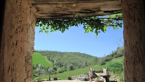 A rustic stone archway leading to a gravel area with a bench and potted plants, overlooking a green hillside. - Cozy Couples Getaway w/ wifi (Pergola)