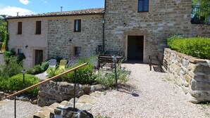 A stone building with a courtyard, featuring a gravel path, outdoor seating, and a small garden area. - Cozy Couples Getaway w/ wifi (Pergola)