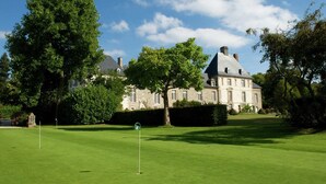 A large, historic building with a well-maintained lawn and a golf flag. - Peaceful Garden Retreat, Epiniac (Epiniac)