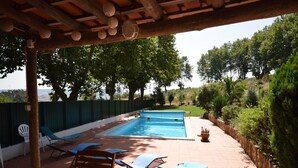 A swimming pool with lounge chairs and a wooden pergola overhead.