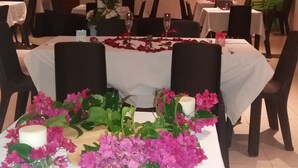 Un comedor con mesas redondas, sillas y un arreglo floral central.