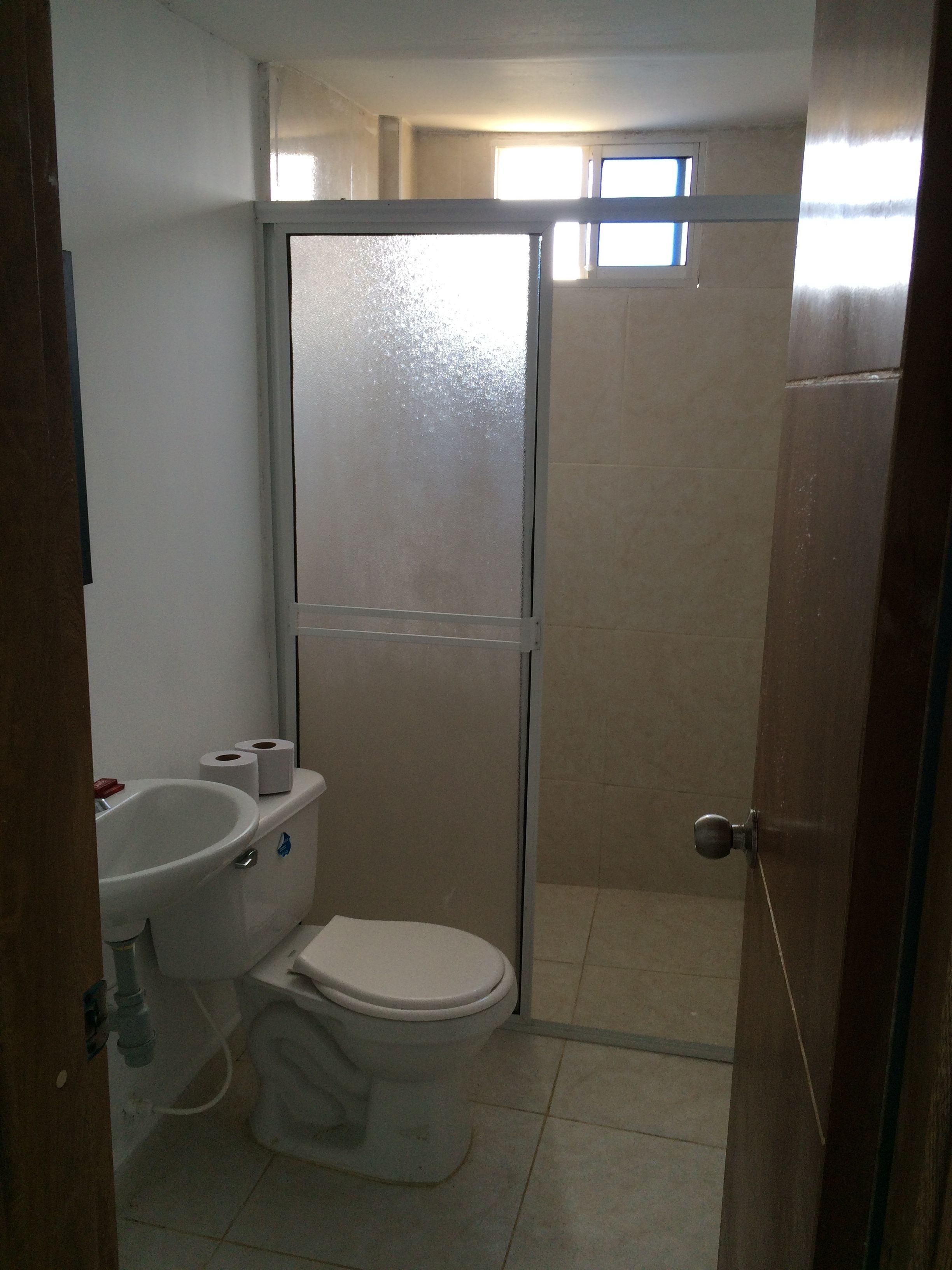 Un baño pequeño con inodoro, lavamanos y cabina de ducha.