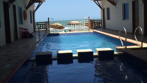 Una piscina con vistas al océano, rodeada de edificios con balcones.