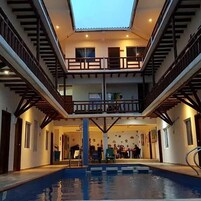 Un edificio de varios niveles con piscina central, balcones de madera y un tragaluz.
