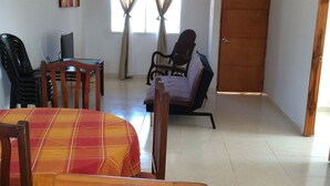 Un comedor con una mesa, sillas, un televisor y un sofá.