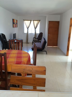 Un comedor con una mesa, sillas, un televisor y un sofá.