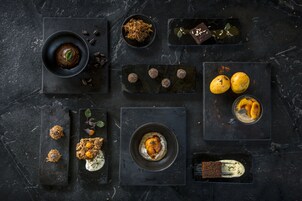 Variedad de postres y bebidas dispuestas sobre bandejas de pizarra oscura.