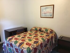 Cozy retreat with a neatly made bed, a compact desk, and a comfortable chair.