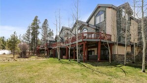 A modern multi-story building with a covered outdoor area and a grassy yard. - Pines 101 Ski in out 4 BR Town House (Breckenridge)