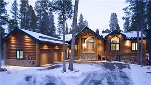 Une cabane en rondins avec des fondations en pierre, un revêtement extérieur en bois et un porche à l’avant.
