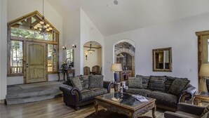 Un salon spacieux, doté d’un grand canapé, d’une table basse et d’une cheminée. On y trouve une porte en bois et une grande fenêtre qui laisse entrer la lumière naturelle.
