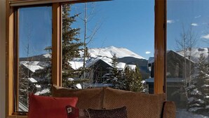Un accogliente soggiorno con una grande finestra che si affaccia su montagne innevate.