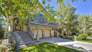 A two-story house with a front porch, a covered garage, and a small balcony. - Windward Way Retreat House (Steamboat Springs)