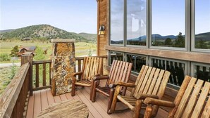A wooden deck with Adirondack chairs and a stone pillar, overlooking a mountainous landscape. - Rocky Fells House (Breckenridge)