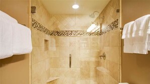 Eine bodenebene Dusche mit gefliestem Boden, einer Handbrause und einer Toilette.