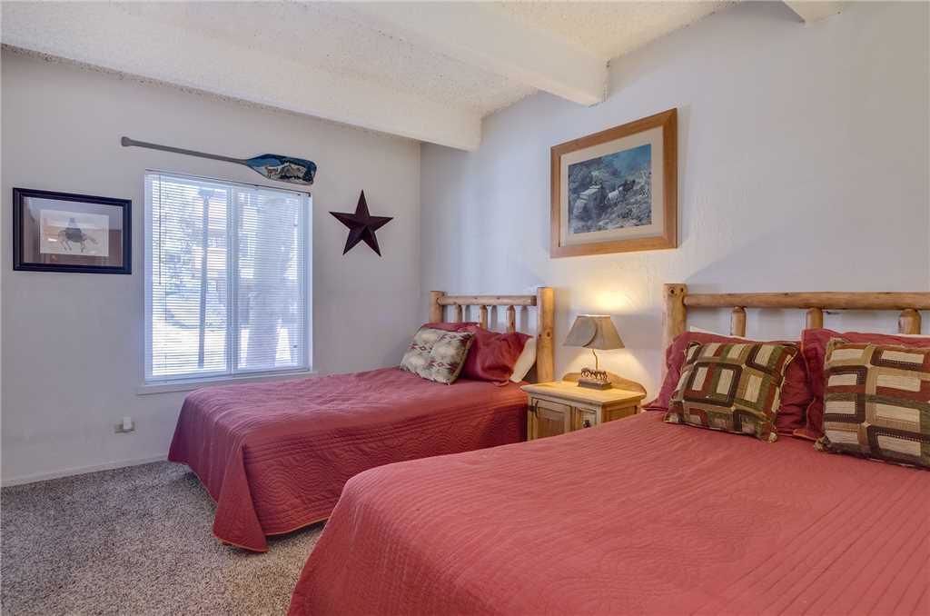 A bedroom with two beds, a star decoration, a framed picture, and a window with blinds.