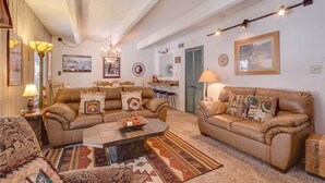 A cozy living room with two leather sofas, a coffee table, and patterned rugs. - Columbine 105 Condo (Breckenridge)