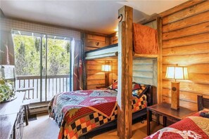Une chambre de style cabane avec un lit superposé, une petite table et un banc près de la fenêtre.