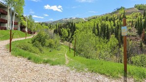 A hotel with a gravel path leading to a lush green landscape, surrounded by trees and hills. - Storm Meadows Townhouse 17 Town House (Steamboat Springs)