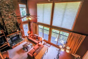 A cozy living room with a stone fireplace, a sofa, and a dining table.