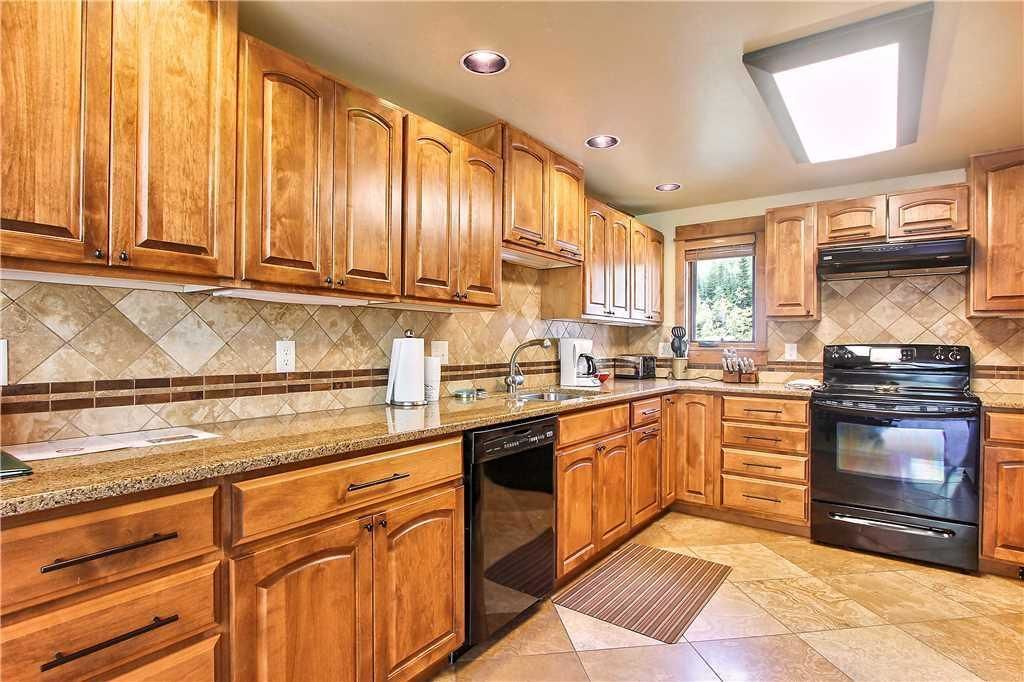 A kitchen with wooden cabinets, a dishwasher, a stove, and a window providing natural light.